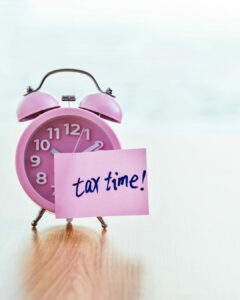 Pink alarm clock with 'tax time!' reminder note - Tax Season Alert